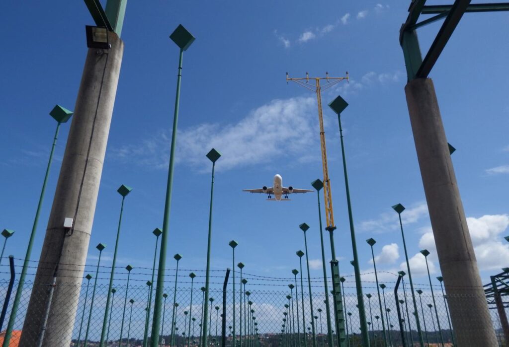 A plane takes off over a series of poles rising from the ground and providing surveillance services.