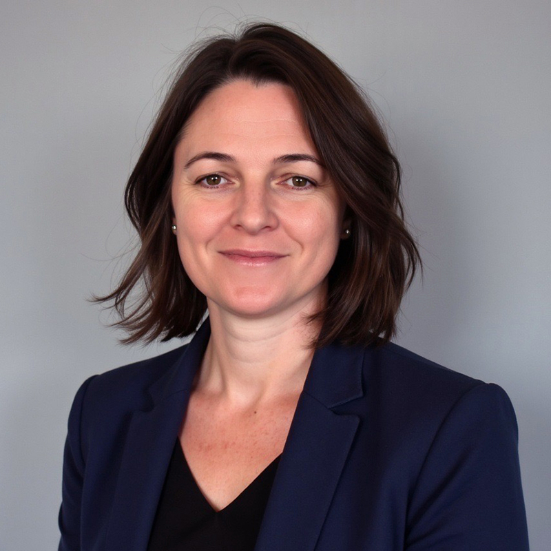 Kerry Pollak smiles while wearing a navy blue suit. She has short dark brown hair.